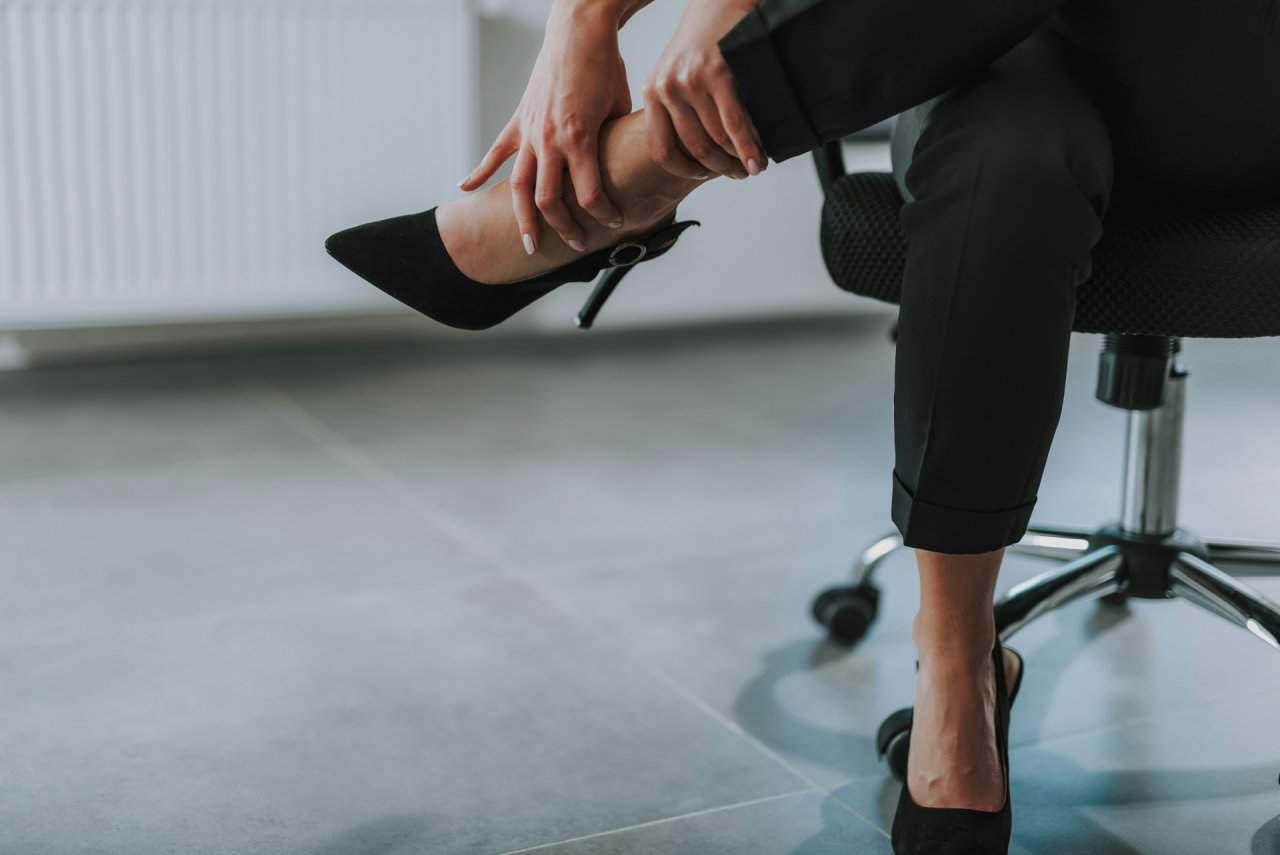 Woman in high heels holding her ankle in pain